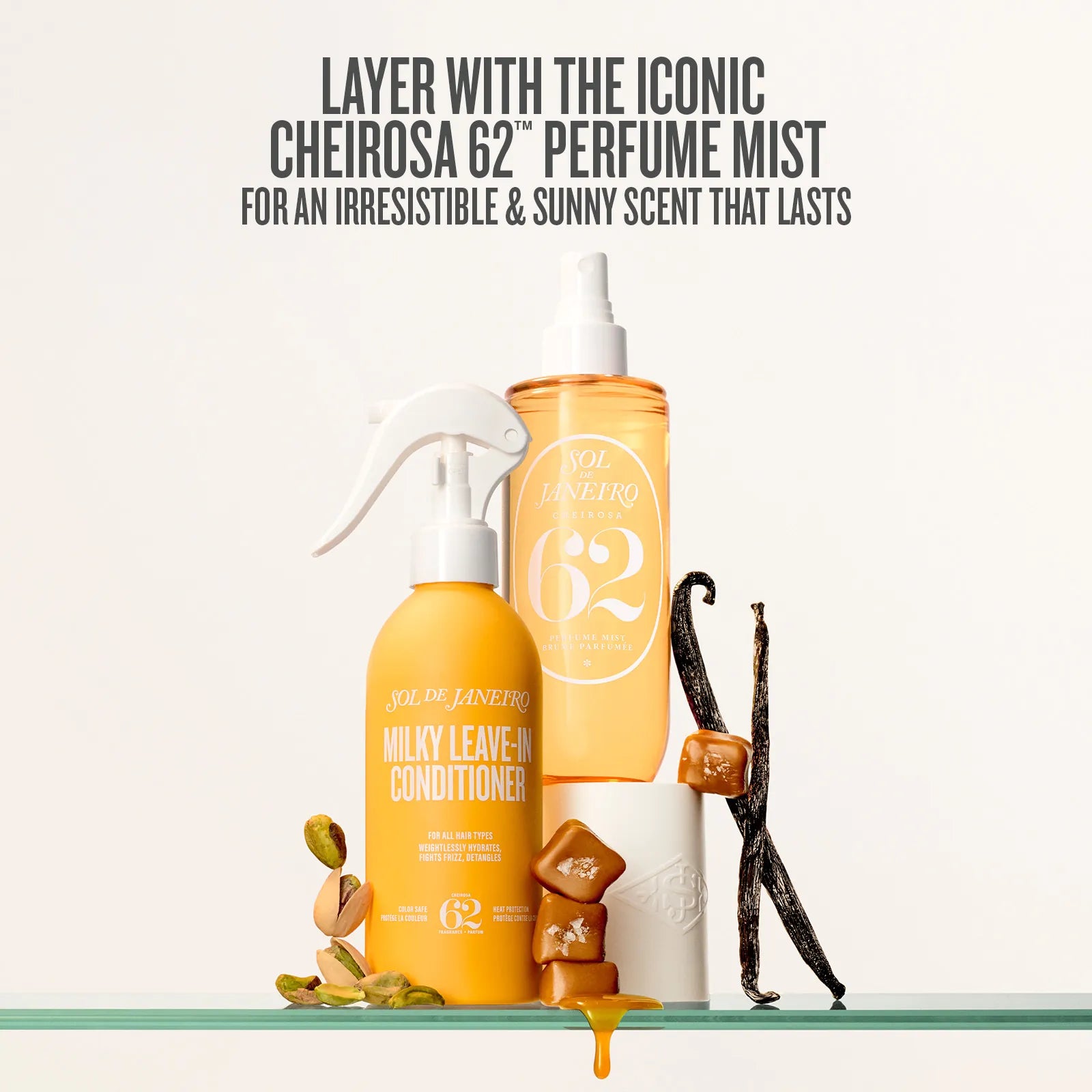Two orange bottles with white sprayers on a glass shelf, vanilla beans, and nuts.