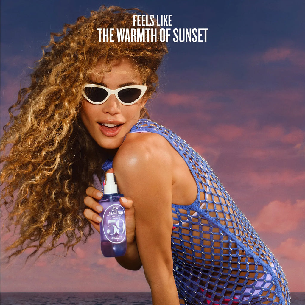 Woman holding a bottle of sunscreen with a sunset background