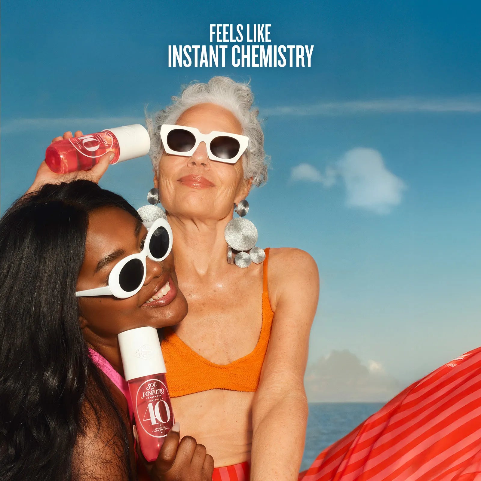 Two women on a beach holding bottles with text 'Feels Like Instant Chemistry' above them.