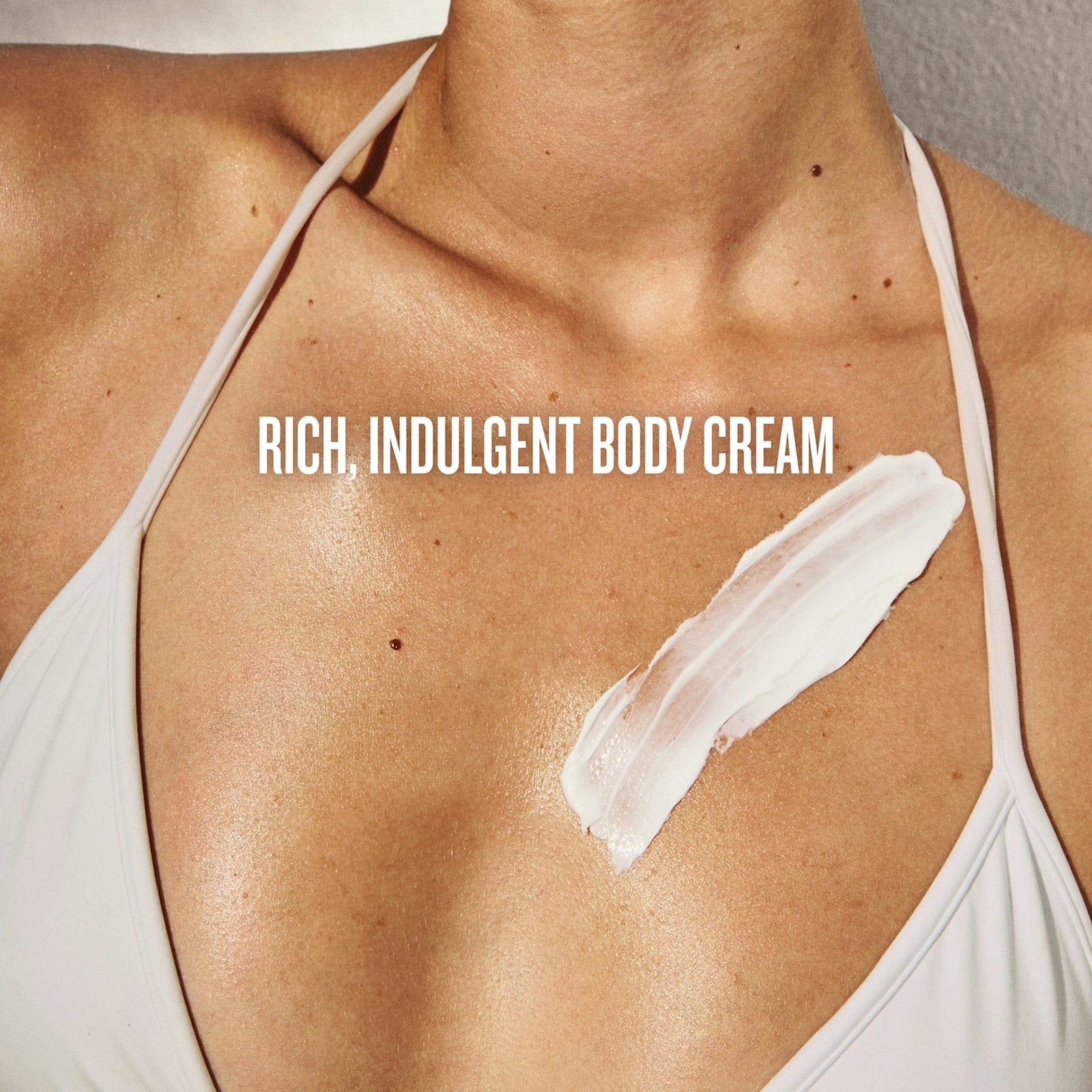 Body cream applied to shoulder with text 'Rich, Indulgent Body Cream' on a neutral background