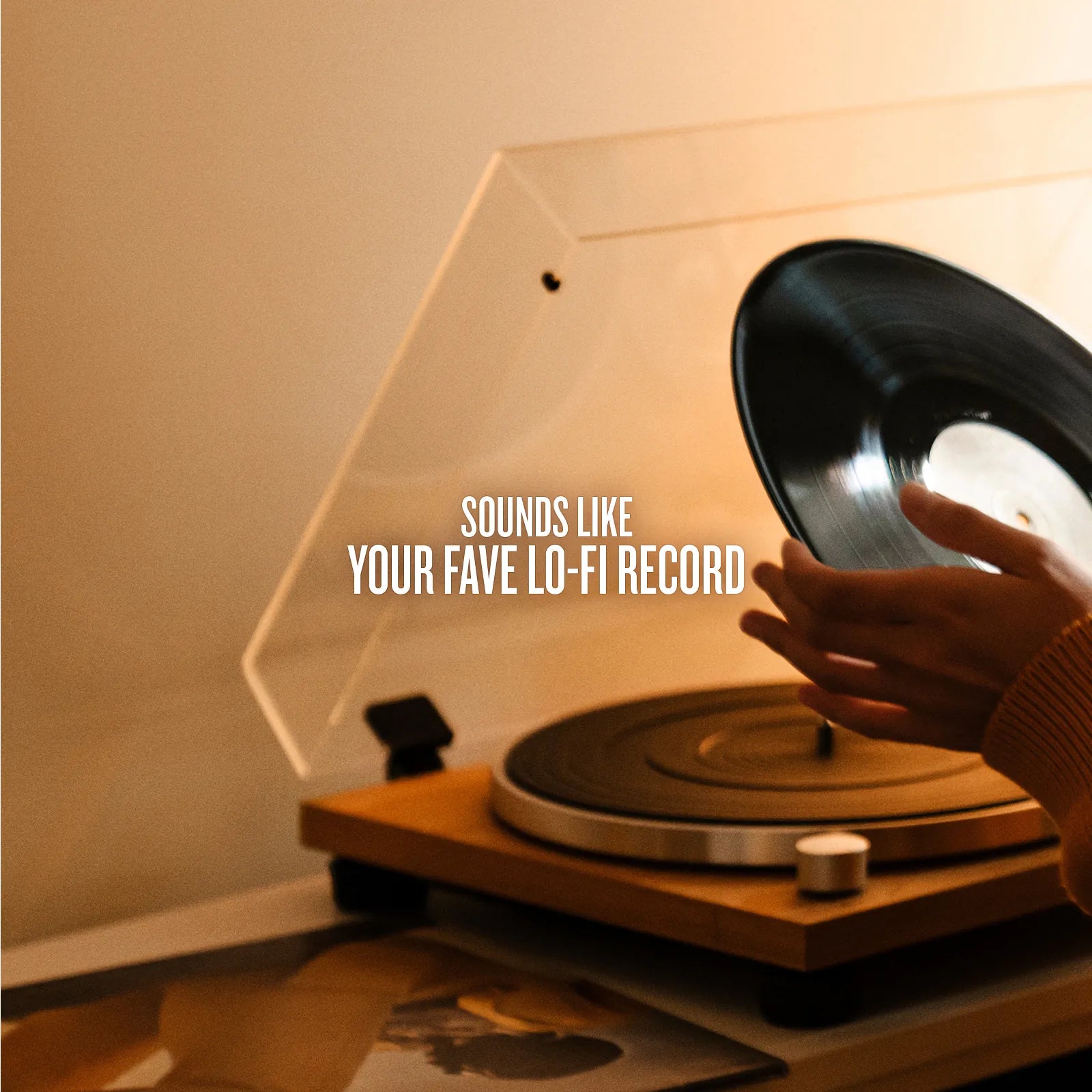 Person placing a vinyl record on a turntable with a warm glow.