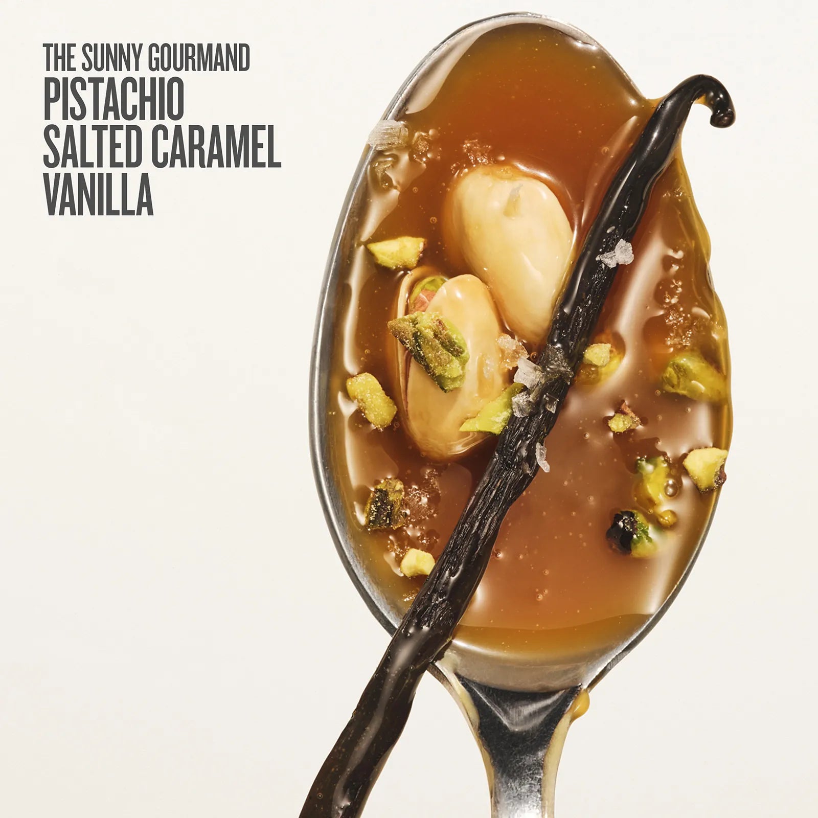 Spoon with dessert featuring salted caramel, vanilla beans, and pistachios on a white background.