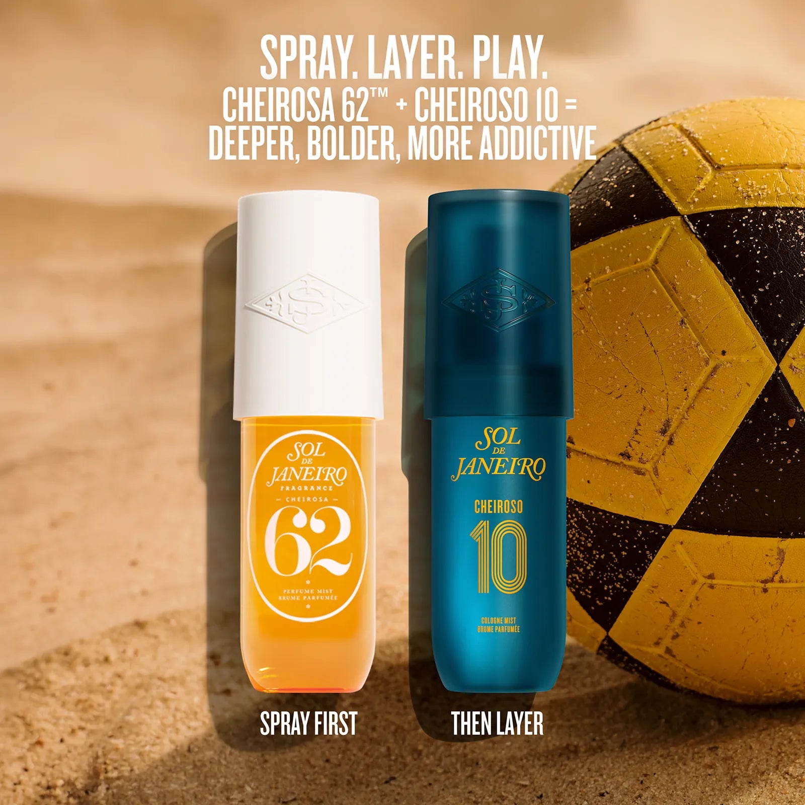 Two Sol Janeiro Cheiroso sunscreen bottles standing upright on a sandy beach-style background next to a yellow soccer ball. White text at the top reads 'SPRAY.