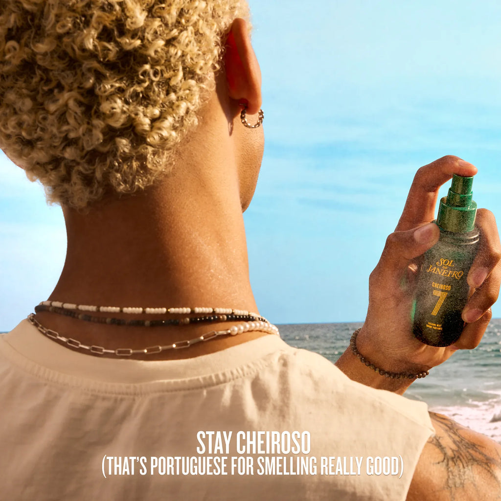 Person holding a spray bottle with a beach in the background, featuring the brand 'Stay Cheiroso'.